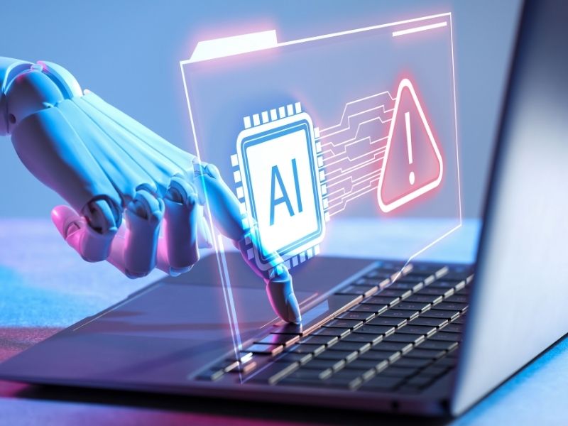 Mano robótica interactúa con una computadora que muestra elementos relacionados con inteligencia artificial y alertas digitales.